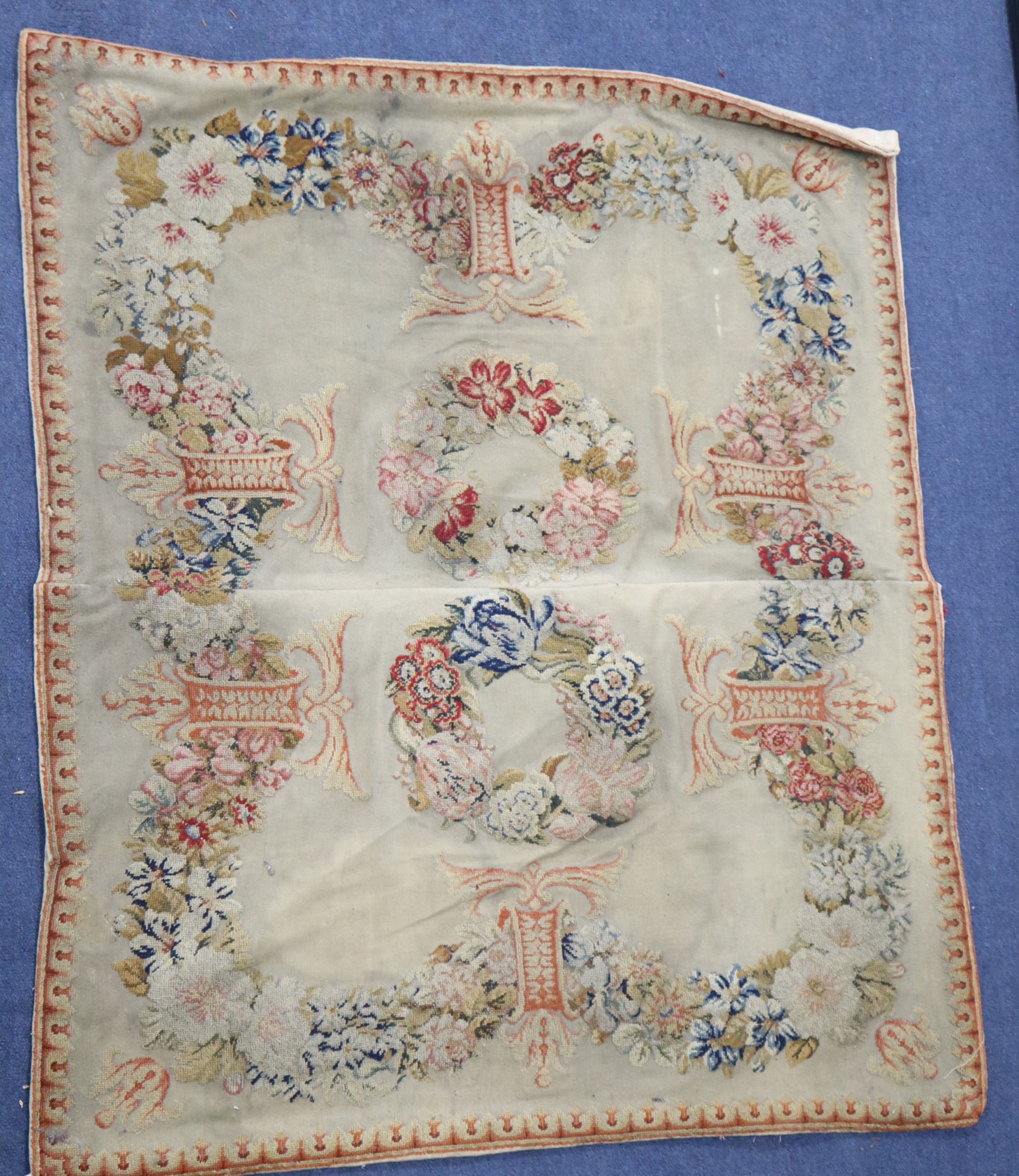 An Antique French needlepoint panel, decorated with a continuous band of flowers and two central wreaths, 98 x 85cm